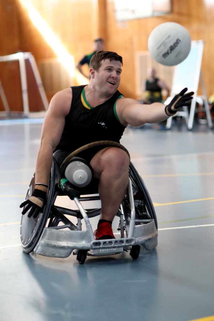 Invictus Games Alumni Mark Daniels reaching for a ball in a wheelchair rugby game