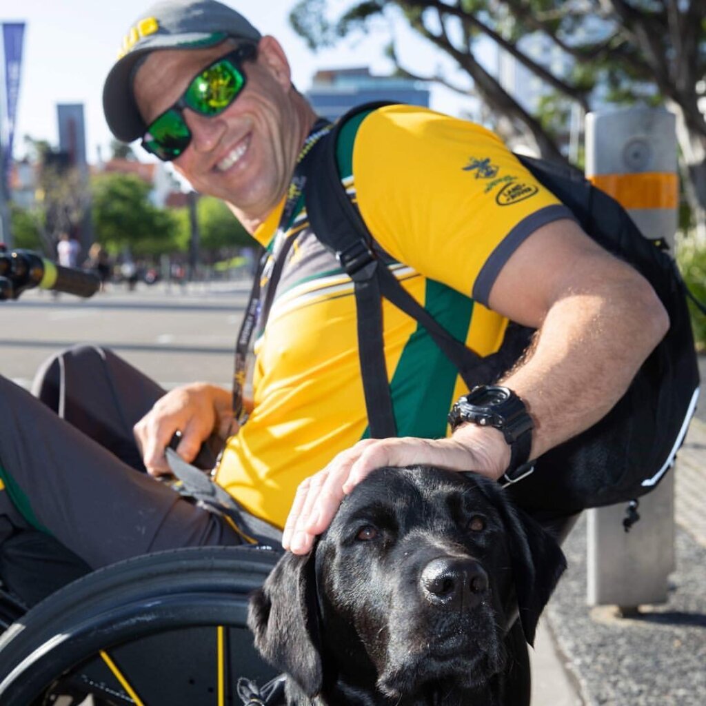 Matt, Invictus Games alumni, poses with his black haired service dog Willow